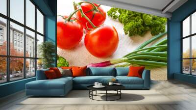 Juicy fresh tomato vegetables and green onion and fragrant green parsley ingredients for a vitamin vegetarian salad on a light wooden background with copy space Wall mural