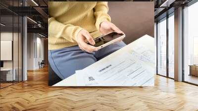 A woman uses a smartphone to connect to a 5G signal. The woman scan the barcode to pay monthly phone bills after receiving an invoice sent to home. Online bill payment concept Wall mural