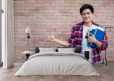 Asian male students wear plaid shirts. Standing next to a brick wall, carrying books, school supplies, preparing for study. Wall mural