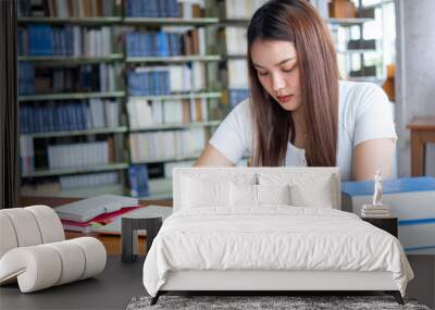 Beautiful Asian female students do their homework and report in the library. Wall mural