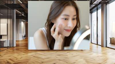 Beautiful Asian woman sitting in front of a mirror. face of a healthy woman applying cream and makeup. Advertisement for skin cream, anti-wrinkle cream, baby face Wall mural