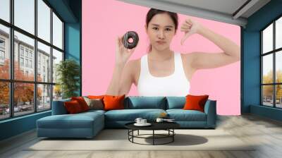 Diet and dieting. Beauty slim female body confuse donut. Woman in exercise clothes achieves weight loss goal for healthy life, crazy about thinness, thin waist, nutritionist.. Wall mural