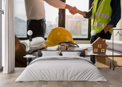 Focused at the desk. behind is Construction workers or architects and engineers shakehands after completing an agreement on an office construction project. Mortgage, rent, buy, sell, move houses. Wall mural