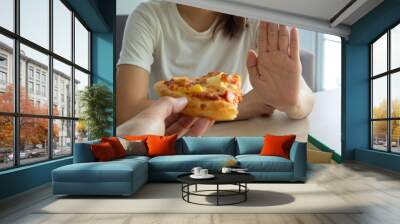 The woman takes care health and weight refuse a piece of pizza that her friend sent. Good health and weight control. diet concept Wall mural