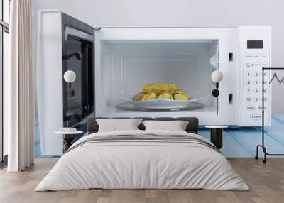 white microwave oven, on a blue wooden surface for heating food Wall mural