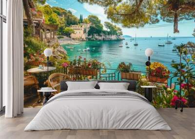 Authentic atmospheric cafe on the shore of the French Riviera under green trees overlooking clear blue water, colorful flowers in the background Wall mural