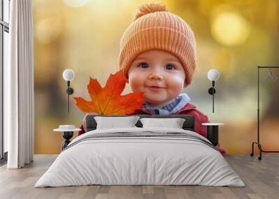 Handsome baby boy in the fall season autumn landscape sunny day, trees and leaves background, holding colorful maple leaf Wall mural