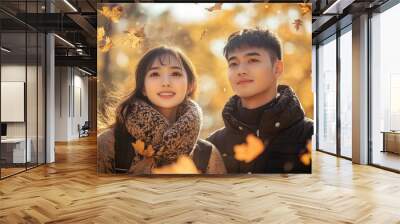 Handsome lovely asian woman and man couple in the fall season autumn landscape sunny day, maple leafs falling on them Wall mural