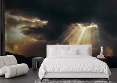 Rays of light shining through dark clouds over mountains. Cinematic scene. Wall mural