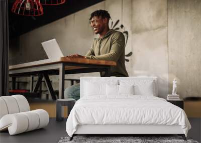 African man with laptop at the table. distance communication, training. online communication Wall mural