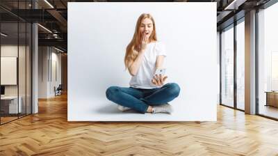 Beautiful young girl talking on the phone, surprise and shock at the girl from news or discounts, in the Studio, isolated background, cheerful and positive Wall mural