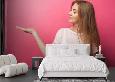 Closeup portrait of happy blonde woman showing the front finger to the side, stands on a pink background,showing something in empty copy space for advertisement.advertising text insertion Wall mural