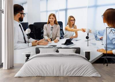 group of young businessmen working and communicating, sitting at an office table together with colleagues Wall mural