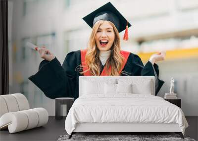 Happy excited beautiful student with a University degree, shows a victory gesture and rejoices. Concept of the graduation ceremony Wall mural