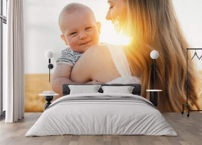 Happy family, young mother in a dress with a cute little baby on a wheat field Wall mural