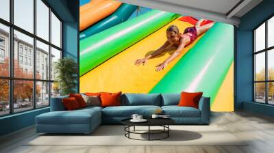 Happy little girl rides a water inflatable slide in a water Park, summer Sunny day, entertainment, water Park Wall mural