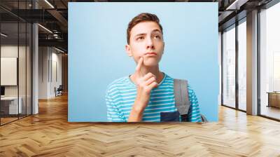 Pensive teenager guy, on a blue background Wall mural