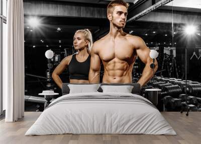 Sportive couple, man and woman in sportswear, in the gym Wall mural