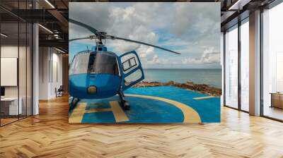 Blue Helicopter for excursion tour on parking near beach in George Town,Cayman island. Helipad is next to the sea. Beautiful ocean is on a background.  Wall mural