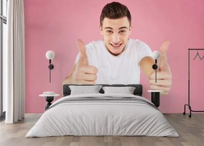 A man in a white t-shirt gestures with his hands emotions pink background studio cropped view Wall mural