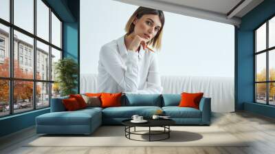 A woman sits on a sofa In a bright room in a shirt and papers  Wall mural