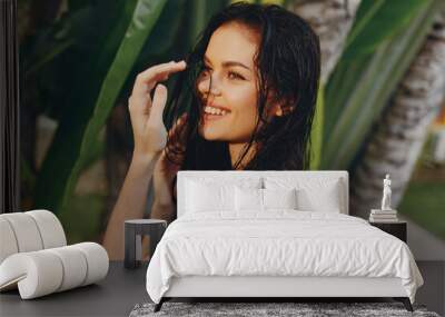 Attractive young female with wet hair in front of palm tree, making eye contact with camera Wall mural