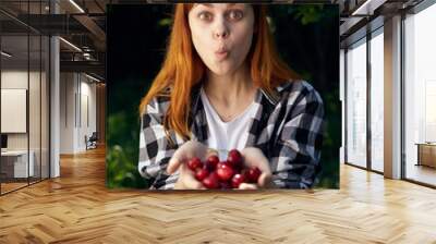 Beautiful young woman in the garden holds a cherry Wall mural