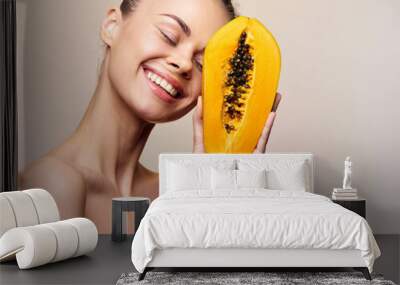 Beautiful young woman with papaya fruit facial mask, skincare and beauty concept, isolated on beige background Wall mural