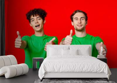 Cheerful friends in green t-shirts gesturing with hands emotions red background Wall mural