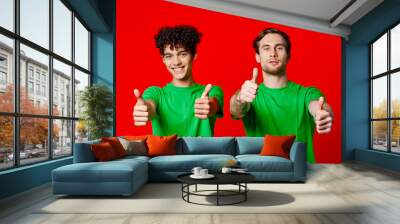 Cheerful friends in green t-shirts gesturing with hands emotions red background Wall mural