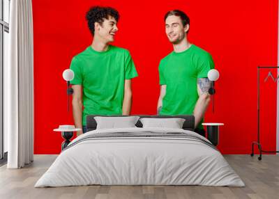 Cheerful friends in green t-shirts hold on to the face of emotion Wall mural