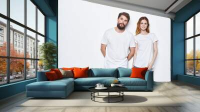 Cheerful man and woman in white t-shirts and jeans design studio light background Wall mural