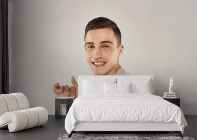 cheerful man gesturing with his hands in a white t-shirt light background cropped view Wall mural