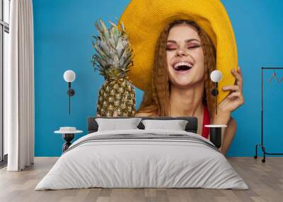 cheerful pretty woman in a hat Pineapple in hands Exotic relaxation blue background Wall mural