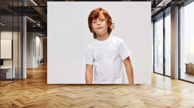 Cheerful red-haired boy in white t-shirt gray background  Wall mural