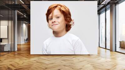 Cheerful red-haired child in a white T-shirt smile studio close-up  Wall mural