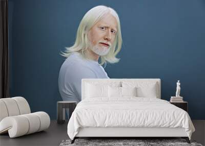 elderly man with long white hair and beard displays self confidence against a muted blue background, showcasing a calm and introspective expression and casual attire Wall mural