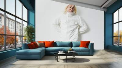 Elderly man with long white hair wearing a stylish white jacket against a plain white background, exuding a modern and artistic vibe, showcasing unique fashion choices and individuality Wall mural