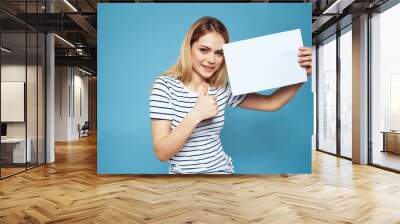 Emotional woman holding a sheet of paper in her hands lifestyle close-up blue background Copy Space Wall mural