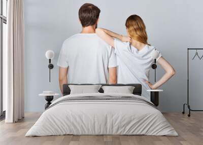 man and woman in white t-shirts stand with their backs light background mockup Wall mural