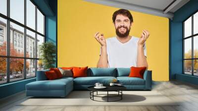 Man gesturing with hands emotions lifestyle white t-shirt yellow isolated background Wall mural