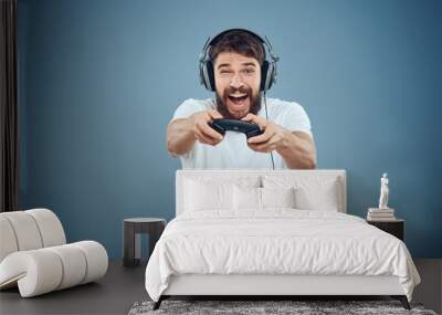 Man in headphones controller in hands playing game console lifestyle emotions blue background white t-shirt Wall mural