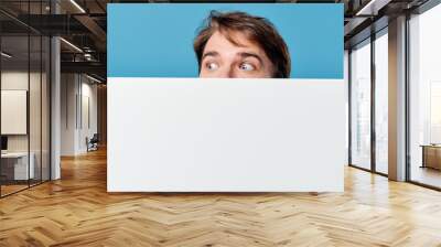 man peeking out from behind banner cropped view advertisement copy space blue background Wall mural