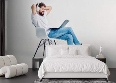 man with headphones sitting on a laptop chair Wall mural