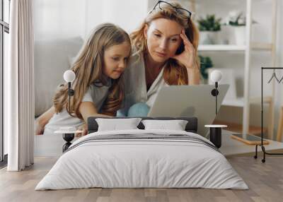 Mother and daughter exploring online resources together at a kitchen table with a laptop Wall mural