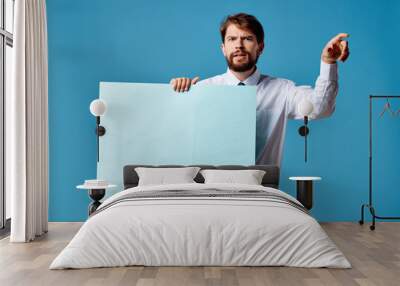 outraged man holding paper blank place free on blue background Wall mural