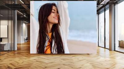 Portrait of a woman smile with teeth in a yellow tank top and white beach shirt with wet hair after swimming on the ocean beach sunset light Wall mural