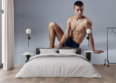 sporty man muscled body posing sitting on workout floor Wall mural