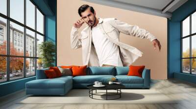 Stylish man smile runs and jumps on a beige background in a white t-shirt and business jacket, flying clothes hero, fashionable clothing style, copy space, space for text Wall mural