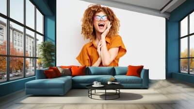 Stylish trendy woman with curly hair wearing colorful sunglasses, bright orange outfit, joyful expression against a clean white background Perfect for fashion and lifestyle themes Wall mural